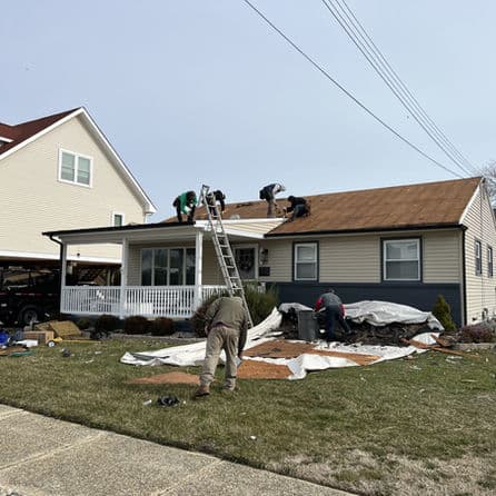 Roof repair work on a residential home with workers and equipment outdoors.