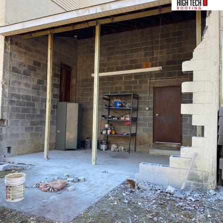 Open garage space with concrete floor, cinder block walls, and storage shelving.