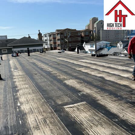 Flat roofing installation viewed from above, showcasing workers and materials on-site.