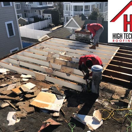 Roofing workers repairing a rooftop with debris, showcasing skilled roof installation process.